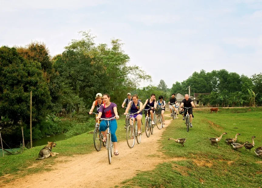 Cyclists on a dirt lane through village fields